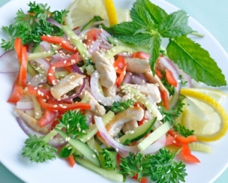 salad with fresh vegetables, seeds, greens, chicken, served on a white plate