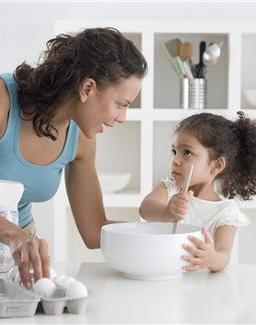 young mother teaching young child to cook